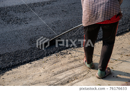 Construction worker using tool spread the hot-mix asphalt road accurately level covering on highway Construction worker using tool spread the hot-mix asphalt road accurately level covering on highway 76176633