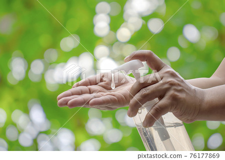 The woman's hand is pressing the hand wash gel for the protection against coronary virus or Covid-19 and the green nature background blurred with the concept of health care and disease prevention. The woman's hand is pressing the hand wash gel for the protection against coronary virus or Covid-19 and the green nature background blurred with the concept of health care and disease prevention. 76177869