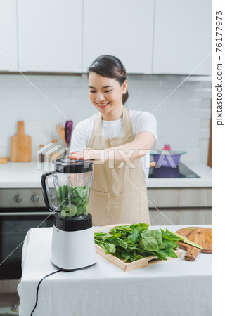 Close-up blender process. Cooking a green spring smoothie. Mixing in a blender bowl Close-up blender process. Cooking a green spring smoothie. Mixing in a blender bowl 76177973