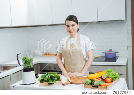 Woman cooking healthy detox smoothie with fresh fruits and green spinach, salad leaves. Lifestyle detox concept Woman cooking healthy detox smoothie with fresh fruits and green spinach, salad leaves. Lifestyle detox concept 76177974
