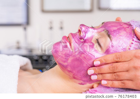 Cosmetologist making massage the skin of the forehead. Woman in a spa salon on cosmetic procedures for facial care. Beautician applies a woman a therapeutic cream on her face. . Cosmetologist making massage the skin of the forehead. Woman in a spa salon on cosmetic procedures for facial care. Beautician applies a woman a therapeutic cream on her face. . 76178403