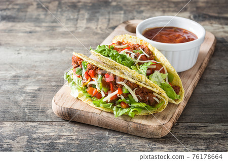 Traditional Mexican tacos with meat and vegetables on wood Traditional Mexican tacos with meat and vegetables on wood 76178664