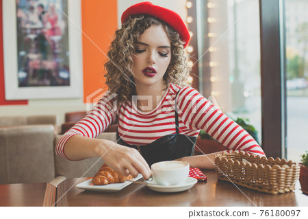 Lovely young woman drinking coffee in city street cafe 76180097