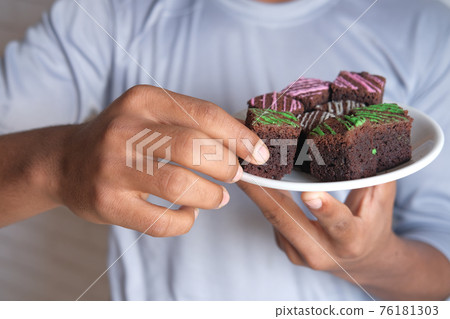 young man eating brownie on plate young man eating brownie on plate 76181303