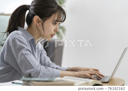 Profile of a young woman typing on a computer Profile of a young woman typing on a computer 76182162