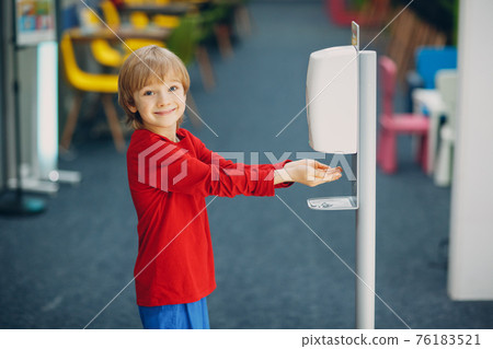 Child smiling boy kid using automatic alcohol gel dispenser spraying on hands sanitizer machine antiseptic disinfectant, new normal life after Coronavirus COVID-19 pandemia Child smiling boy kid using automatic alcohol gel dispenser spraying on hands sanitizer machine antiseptic disinfectant, new normal life after Coronavirus COVID-19 pandemia 76183521