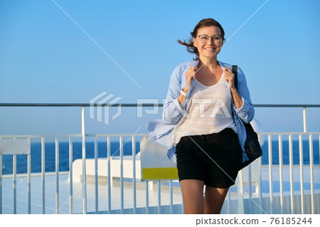 Happy middle aged woman on deck of cruise ship, copy space 76185244