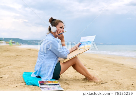Relaxation on sea, mature woman in headphones with watercolors painting 76185259