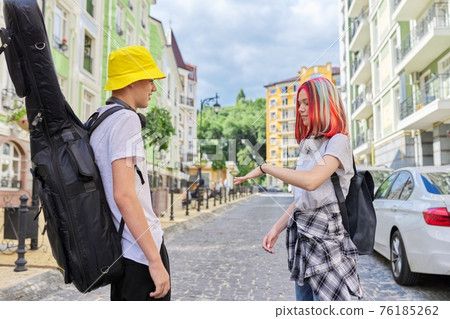 Talking guy with guitar in case and beautiful girl with trendy dyed colored hai 76185262