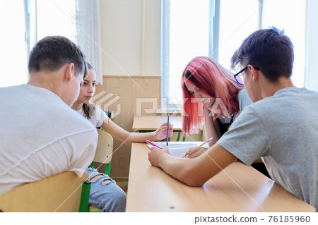 Group of teenage students in the classroom sitting at their desks Group of teenage students in the classroom sitting at their desks 76185960