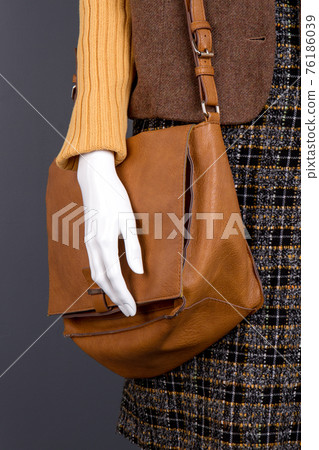Brown leather handbag and mannequin hand. Brown leather handbag and mannequin hand. 76186039