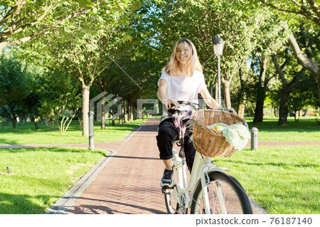Young beautiful woman on vintage bike with basket rides on nature 76187140