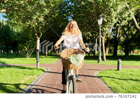 Young beautiful woman on vintage bike with basket rides on nature Young beautiful woman on vintage bike with basket rides on nature 76187142