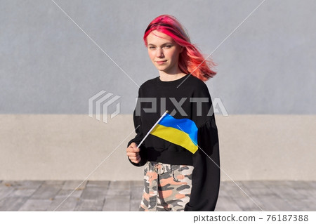 Female student teenager with Ukraine flag, gray outdoor wall background Female student teenager with Ukraine flag, gray outdoor wall background 76187388