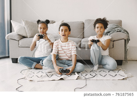 Children play in video games at home on floor Children play in video games at home on floor 76187565