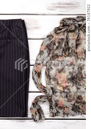 Flat lay folded trousers and trendy blouse. 76187922