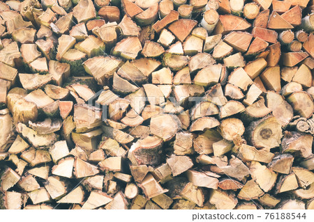 Logs of firewood . Fuel for stove heating. Country life. Wooden firewood stacked wall. Natural wood background. Firewood stacked in several rows 76188544