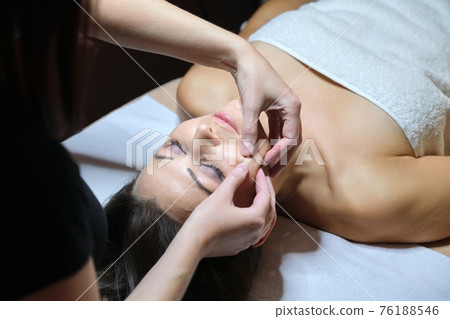 Mature woman face massage, beautician doing facial spa treatments 76188546