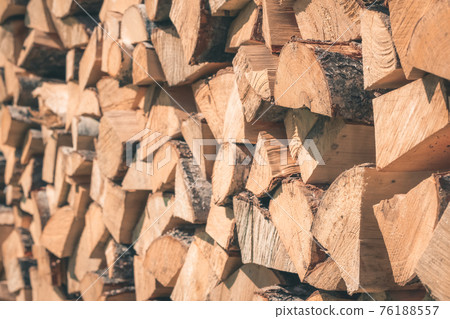 Firewood or fuelwood stacked by a wall. Wooden pile prepared for winter. Fuel for countryside fireplace. Forest timber energy concept, Texture woodpile closeup 76188557