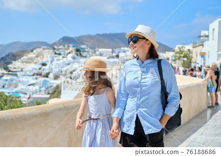 Tourists mom and daughter walking around the famous Greek island of Santorini 76188686