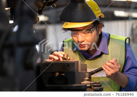 A worker in glasses standing near industrial equipment and verifies production. man operating machine in the factory 76188940