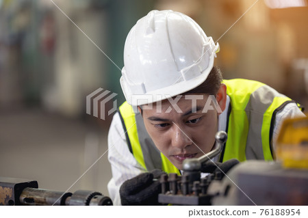 A worker in glasses standing near industrial equipment and verifies production. man operating machine in the factory A worker in glasses standing near industrial equipment and verifies production. man operating machine in the factory 76188954