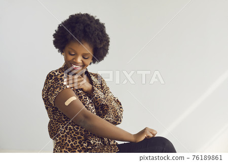 Happy vaccinated african american woman with medical patch on arm portrait Happy vaccinated african american woman with medical patch on arm portrait 76189861