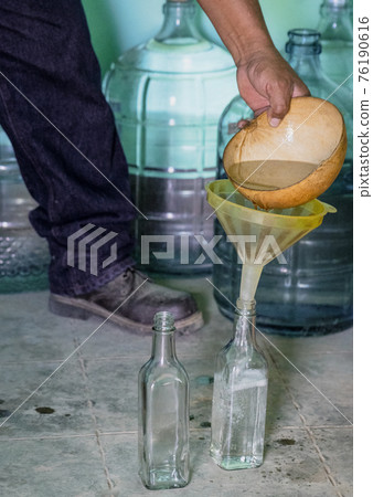 Mezcal is poured into a bottle for sale from a small distillery Mezcal is poured into a bottle for sale from a small distillery 76190616