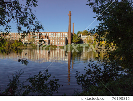 A 19th century textile mill has been renovated for modern use, seen reflected in the neighboring 76190815