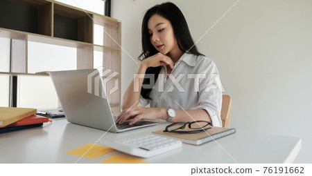 Asian businesswoman working with portable laptop computer 76191662