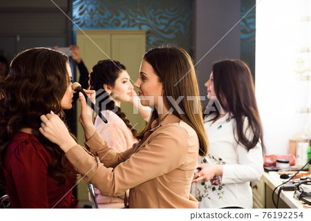 Process of making makeup. Make-up artist working with brush on model face. Portrait of young woman Process of making makeup. Make-up artist working with brush on model face. Portrait of young woman 76192254