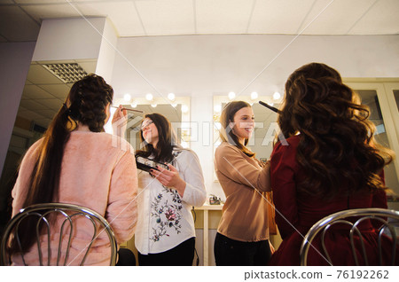Professional makeup artists working with beautiful young women. 76192262