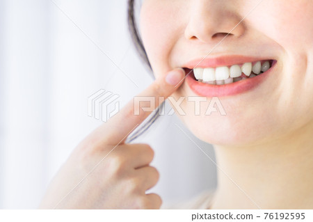 Young woman pointing to teeth Young woman pointing to teeth 76192595
