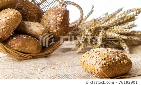 Bakery products. Rye bakery with crusty loaves and crumbs. Fresh loaf of rustic traditional bread with wheat grain ear or spike plant on natural cotton background. Concept - Cooking at Home. Bakery products. Rye bakery with crusty loaves and crumbs. Fresh loaf of rustic traditional bread with wheat grain ear or spike plant on natural cotton background. Concept - Cooking at Home. 76192901