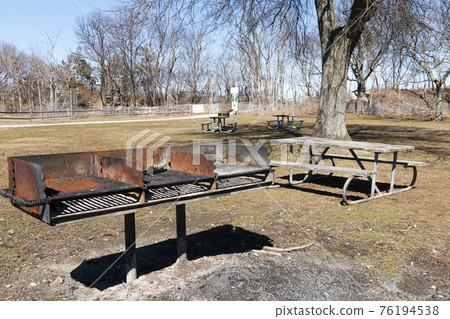 Triple barbeque grill in park with picnic benches Triple barbeque grill in park with picnic benches 76194538