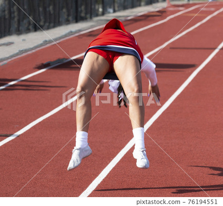 Cheerleader perfomrning flips on a red track Cheerleader perfomrning flips on a red track 76194551