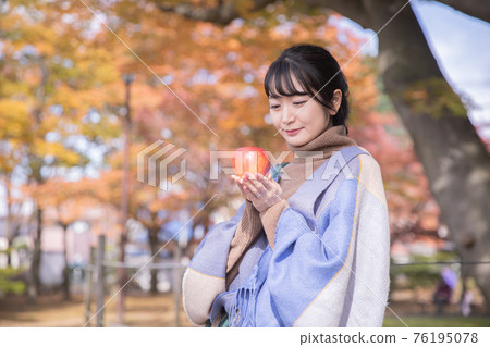 Woman eating an apple in an autumn park Woman eating an apple in an autumn park 76195078