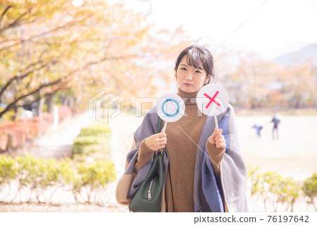 A woman making a cross in an autumn park A woman making a cross in an autumn park 76197642