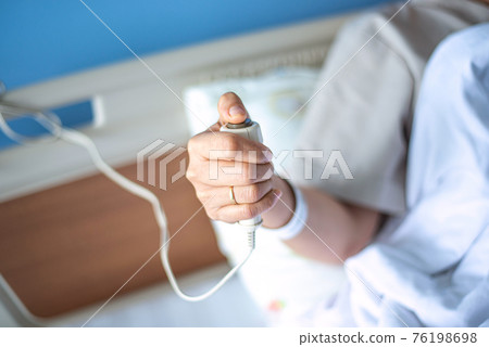 Patient pressing nurse call button holding help emergency health care Patient pressing nurse call button holding help emergency health care 76198698