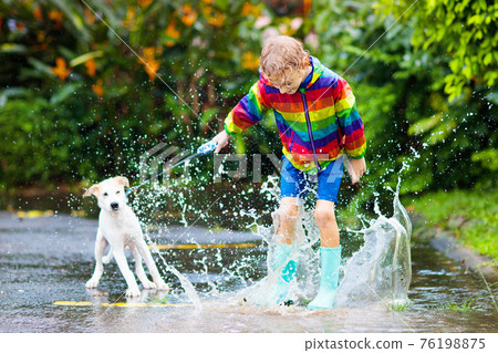 Kids in puddle in autumn rain. Waterproof wear Kids in puddle in autumn rain. Waterproof wear 76198875