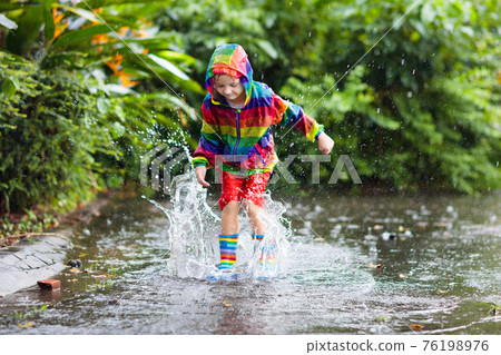 Kids in puddle in autumn rain. Waterproof wear Kids in puddle in autumn rain. Waterproof wear 76198976