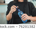 Woman opening the plastic cap of mineral water bottle 76201382