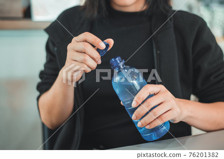 Woman opening the plastic cap of mineral water bottle Woman opening the plastic cap of mineral water bottle 76201382