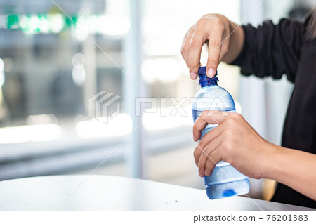 Woman opening bottle of water ,Don't forget to hydrate yourself Woman opening bottle of water ,Don't forget to hydrate yourself 76201383