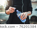 Female athlete opening the plastic cap of mineral water bottle 76201384