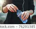 Female athlete opening the plastic cap of mineral water bottle 76201385