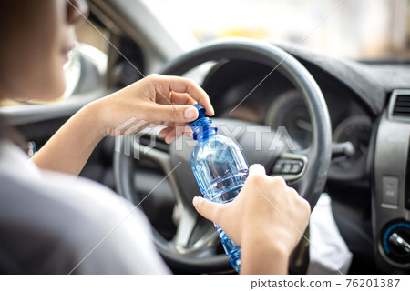 Women drink water during driving in the morning. Women drink water during driving in the morning. 76201387
