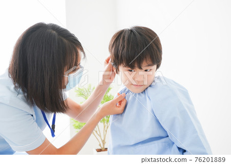 Boy undergoing ear examination 76201889