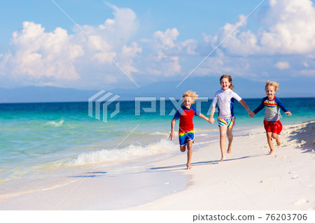 Kids playing on beach. Children play at sea. 76203706