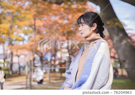 A woman standing in an autumn park 76204963